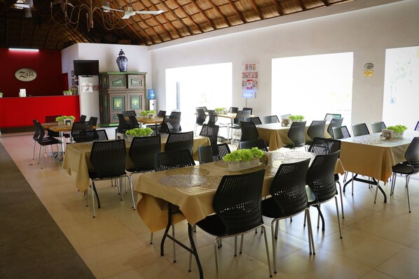 A spacious dining area with multiple tables and chairs, a reception desk, and a television.