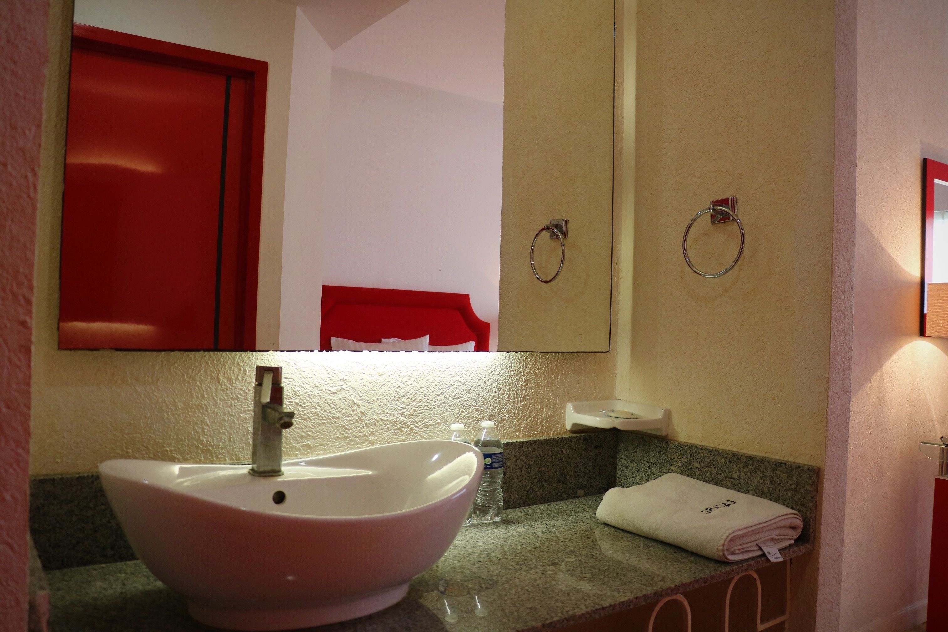 Une salle de bain avec un lavabo blanc, un meuble rouge et un porte-serviettes.