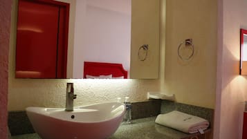 Une salle de bain avec un lavabo blanc, un meuble rouge et un porte-serviettes.