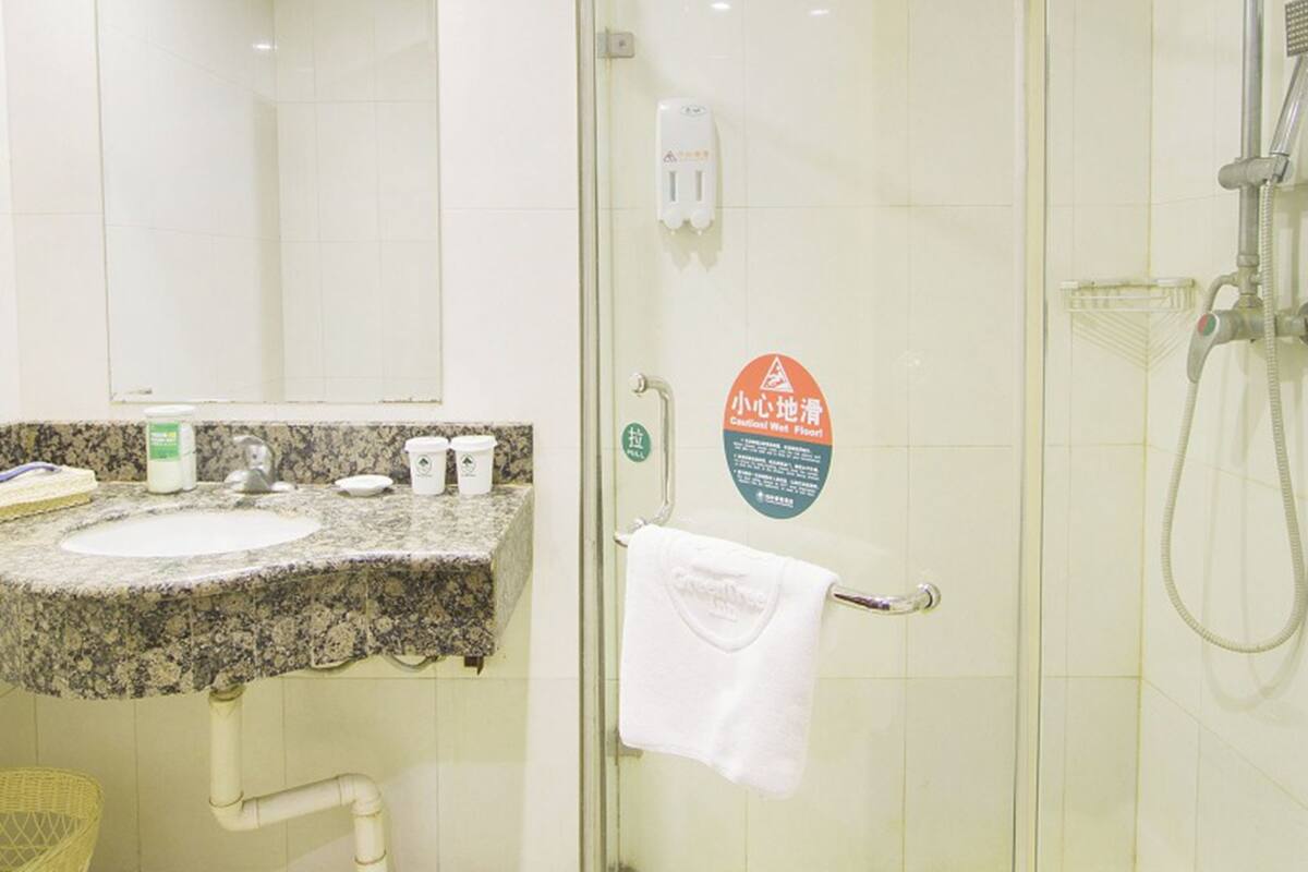 A bathroom with a granite countertop sink, a glass shower enclosure, and a towel rack.