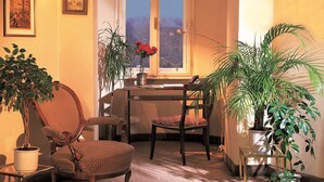 A cozy room with a dining table, chairs, a potted plant, and a window with a view. - Mondial Appartement Hotel (Vienna)