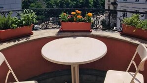 A round table with four chairs on a rooftop terrace, surrounded by potted plants and overlooking a cityscape. - Mondial Appartement Hotel (Vienna)