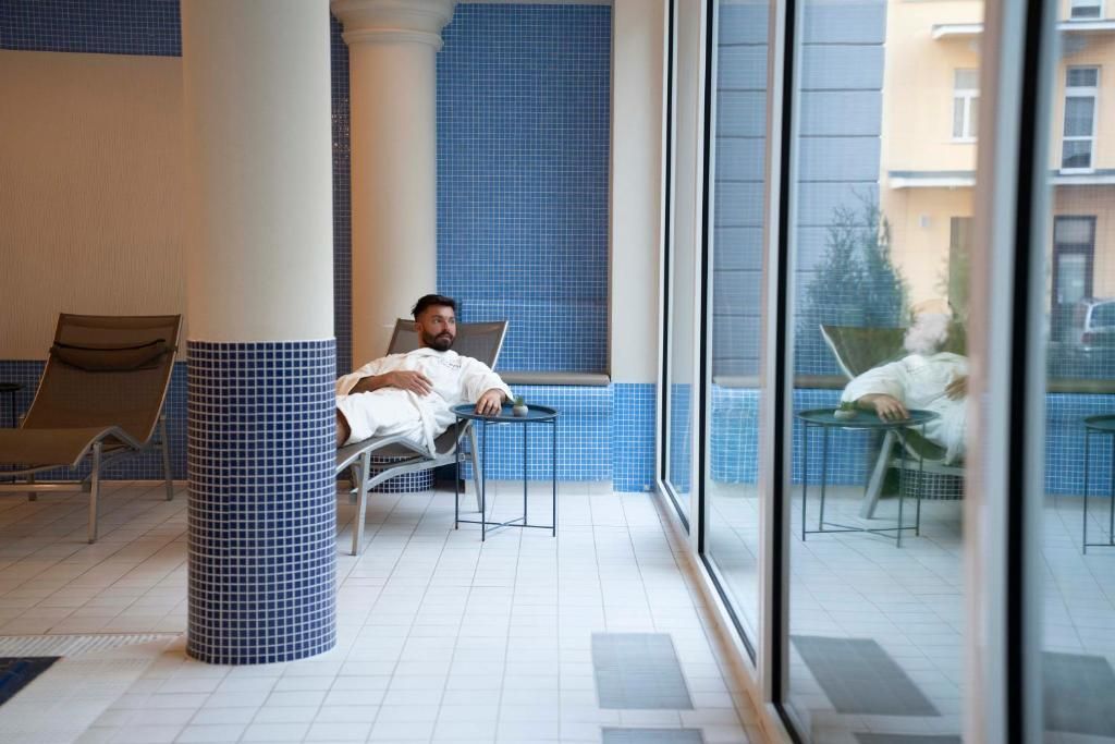 Un vestíbulo de hotel con una zona de estar, un pilar grande y vistas a través de un muro de cristal.