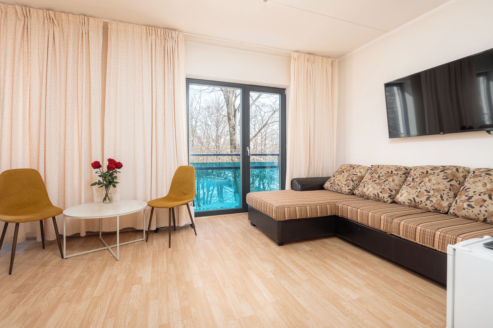 Una sala de estar moderna con un sofá, dos sillones, una mesita y un televisor montado en la pared.
