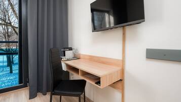 Una habitación moderna con escritorio, silla, televisión y ventana con cortinas.