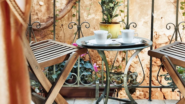 A small outdoor patio with two wooden chairs, a metal table, and a potted plant. - Archontiko Evgenia (Chania)
