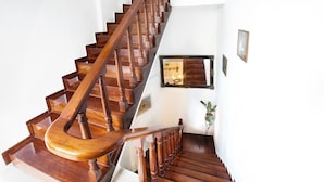 A wooden staircase with a handrail, white walls, and a framed mirror. - Archontiko Evgenia (Chania)