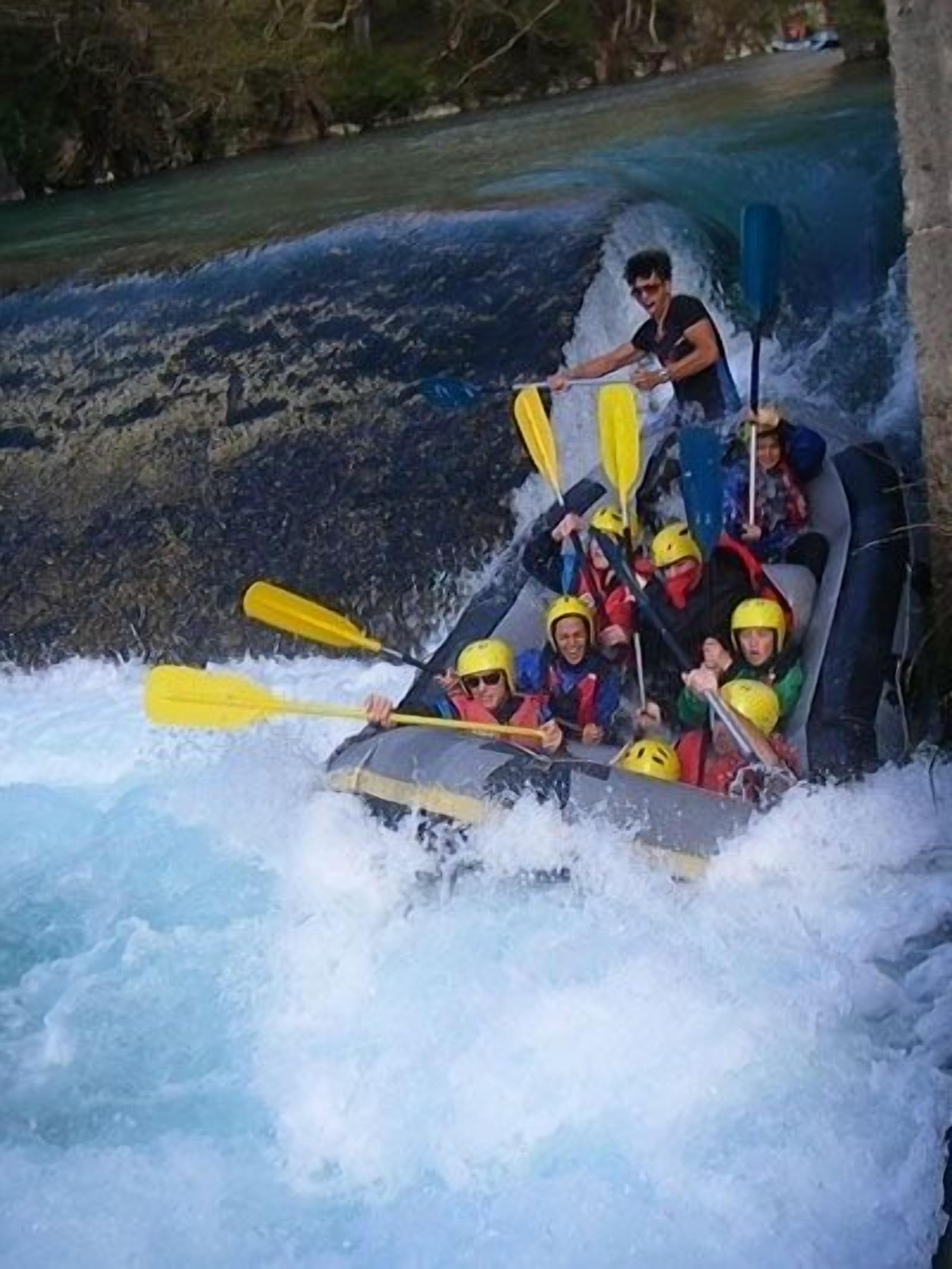 Un grupo de personas en balsas navegando por un río con rápidos.