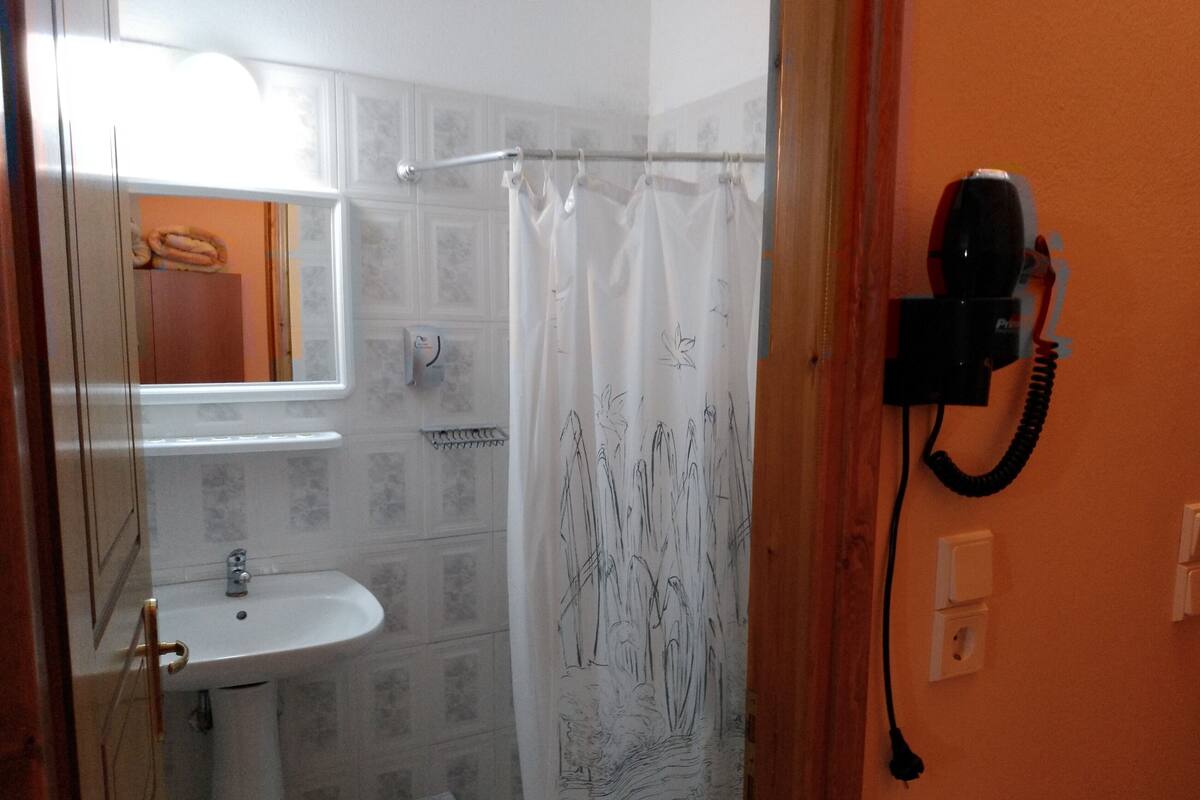 A bathroom with a sink, a shower curtain with a floral pattern, and a telephone mounted on the wall.
