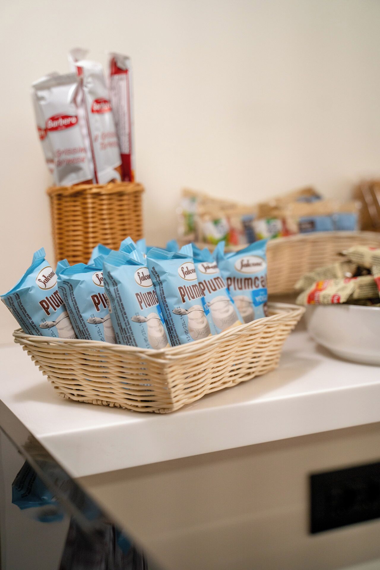 A kitchen counter with a basket containing bags of 'Plum' yogurt and other packaged goods.