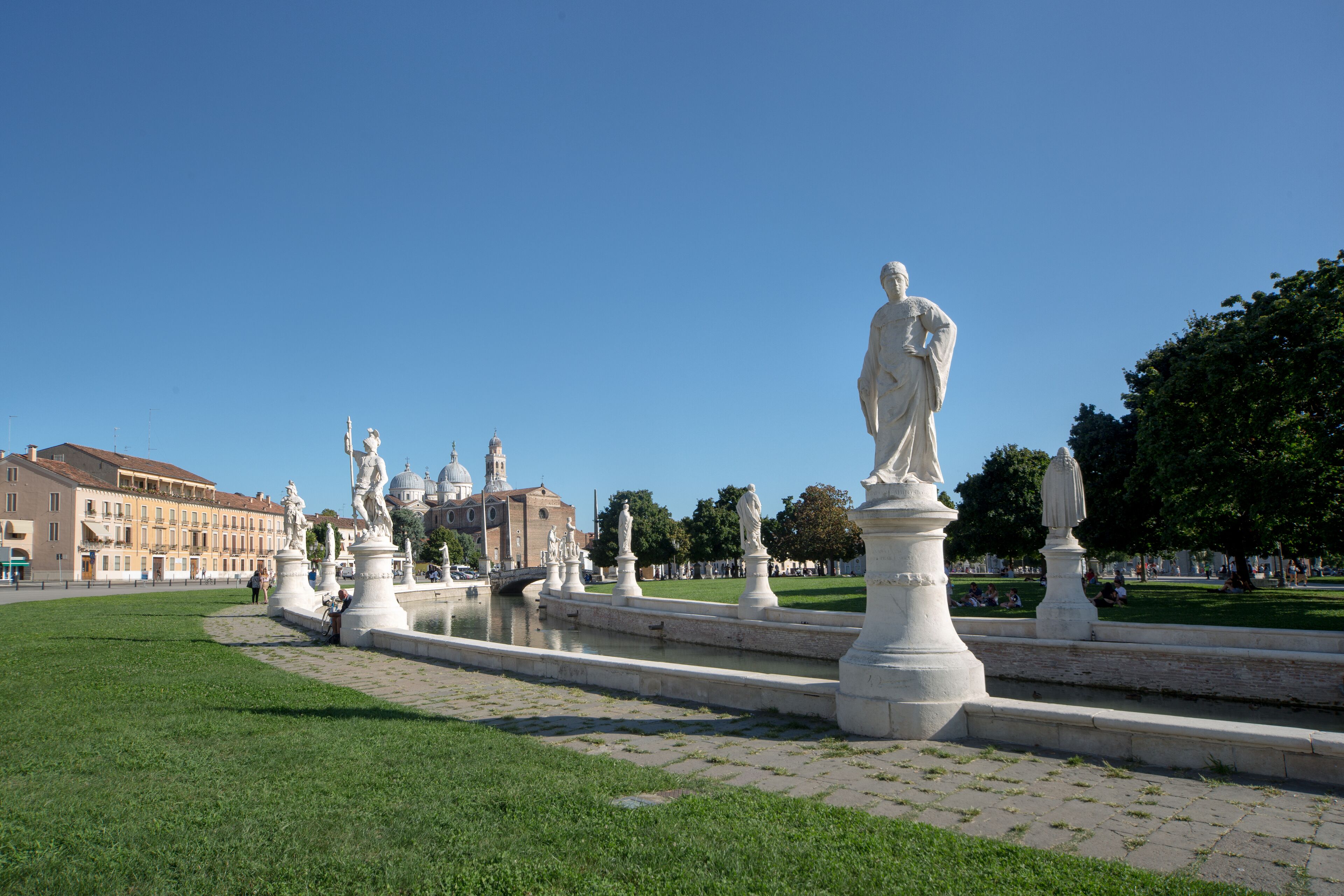 Une place publique ornée de statues, d’une fontaine et d’un bâtiment aux dômes, qui se trouve au fond.