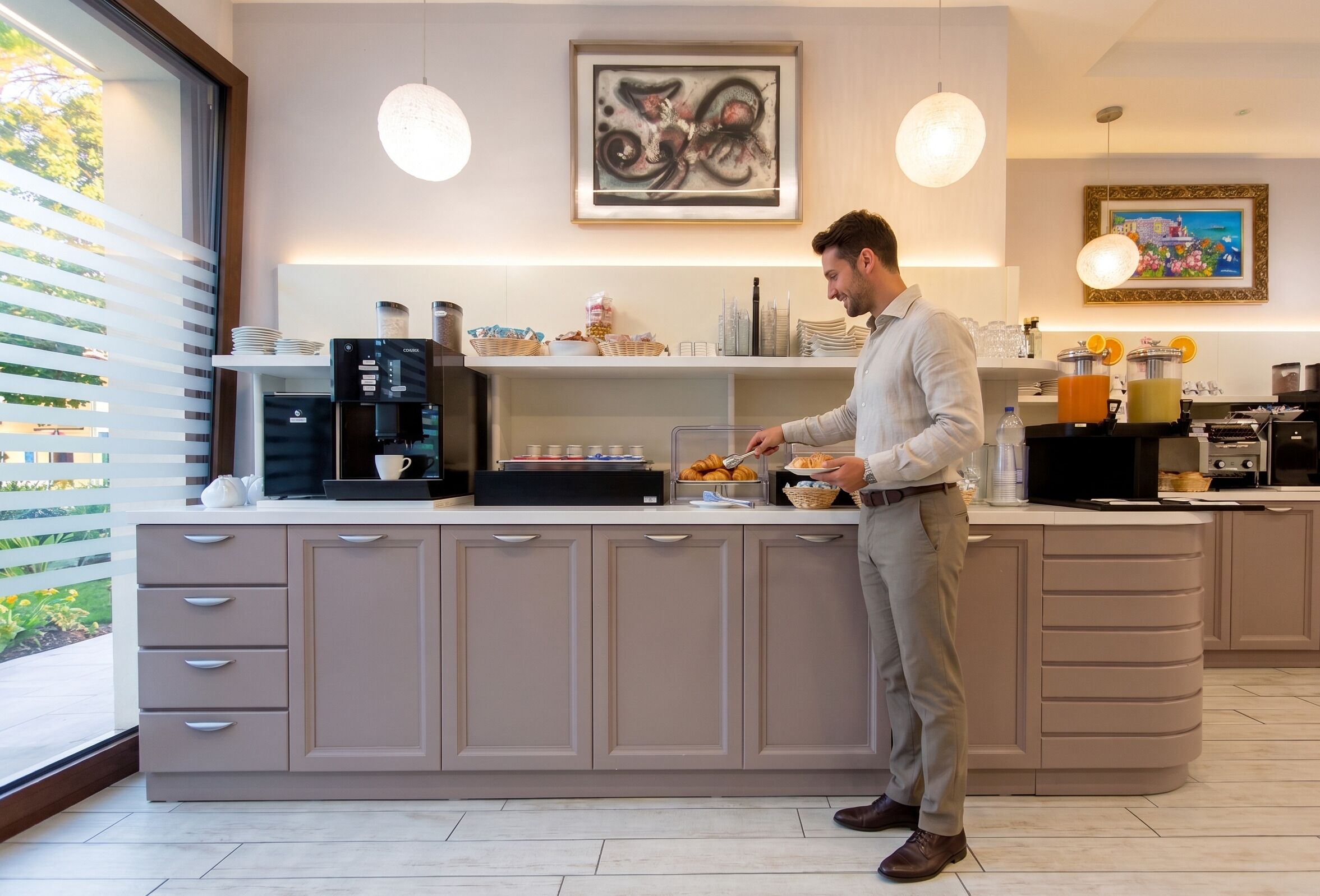 Cocina moderna con cafetera integrada, frutero y una persona preparando alimentos.