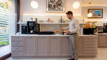 Cocina moderna con cafetera integrada, frutero y una persona preparando alimentos.