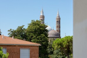 A building with a tiled roof and a garage door, with trees in the foreground. - Hotel Giotto (Padova)