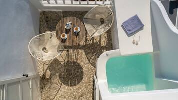Una terraza en la azotea con piscina, dos mesas con sillas y un rincón de descanso.