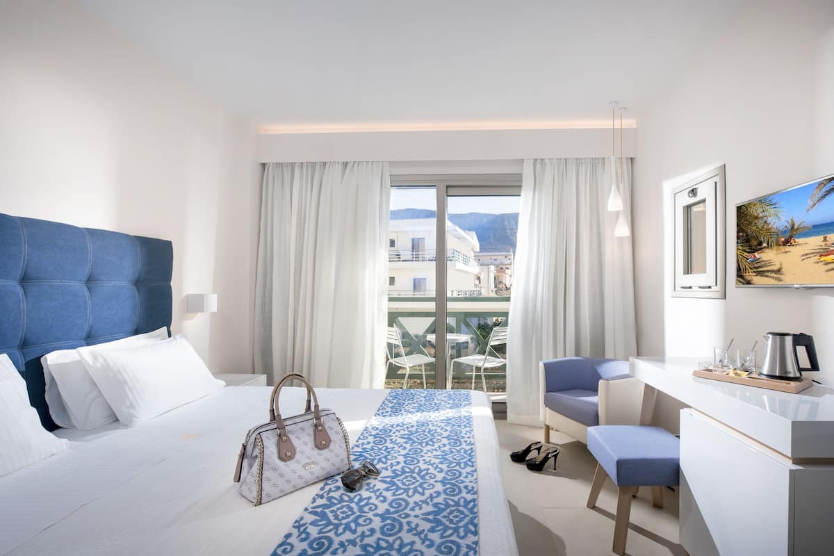 Een hotelkamer met een groot bed, een bureau en uitzicht op de stad.