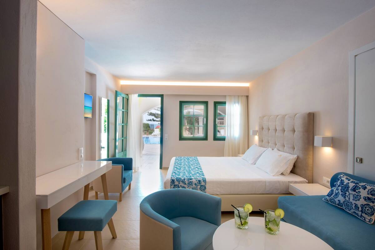 Een hotelkamer met een bed, bureau, stoel en een klein tafeltje met drankjes.
