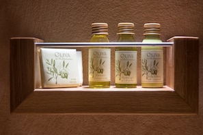 A shelf with four bottles of olive products: soap, shampoo, shower gel, and body lotion.