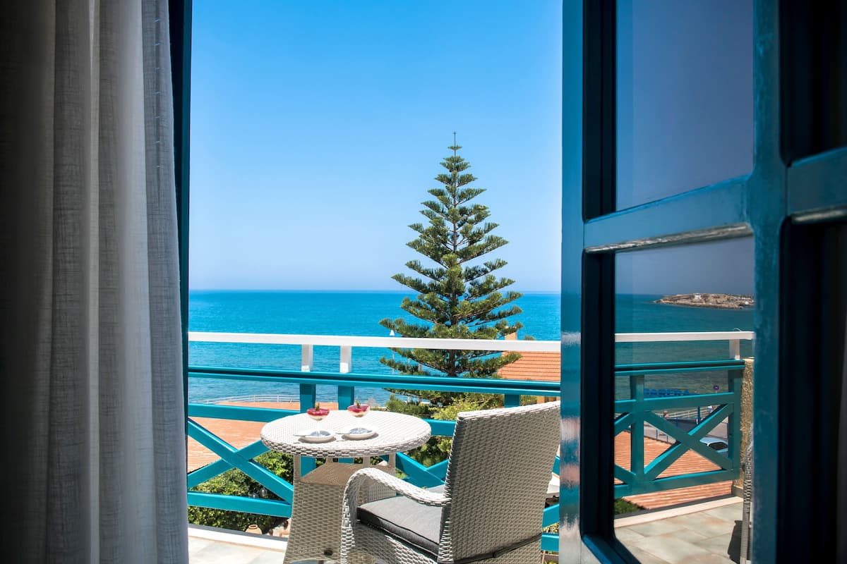 Een balkon met uitzicht op zee, een tafel met stoelen en een potplant.
