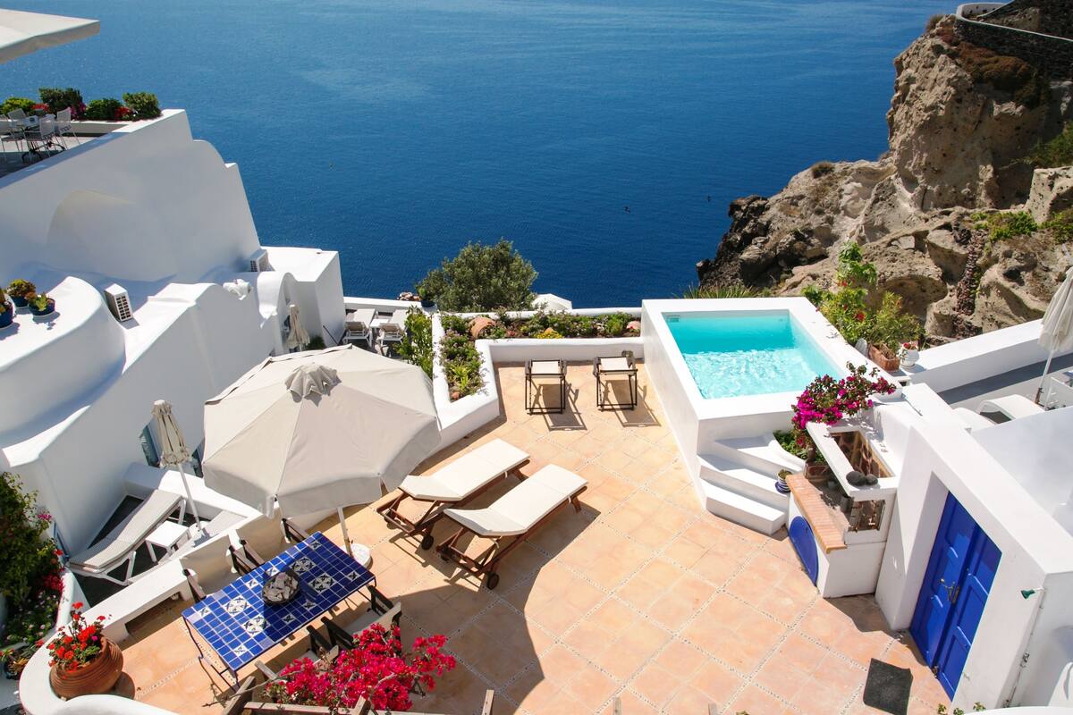 Eine Dachterrasse mit Pool, Liegestühlen und einem Tisch mit Sonnenschirmen.