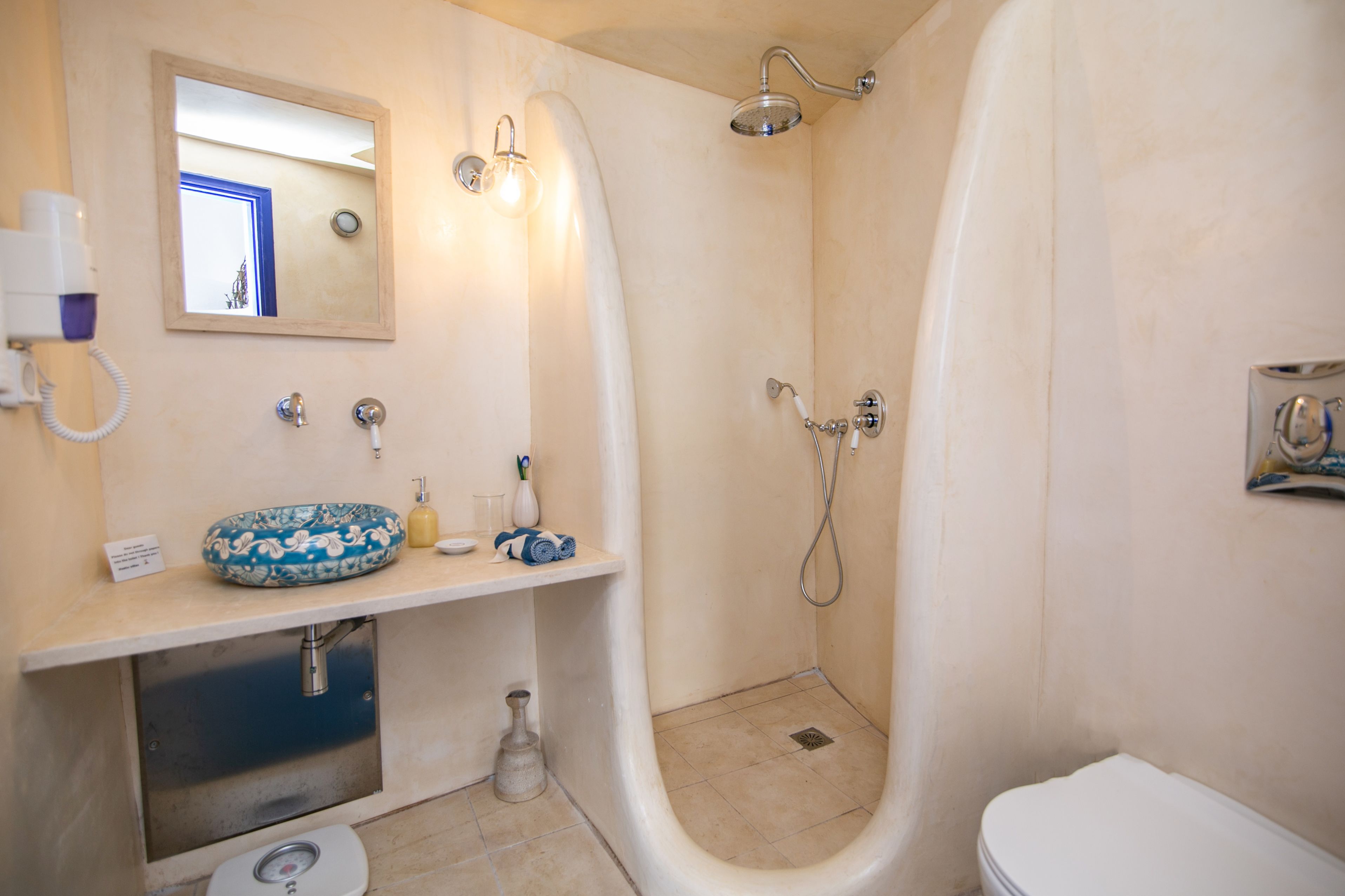A bathroom with a sink, mirror, toilet, and shower.