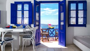 Habitació amb taula blanca, finestres de blau i vista al mar.