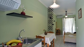 A kitchen with a sink, a fruit basket, a vase with flowers, and a dining area with a table and chairs.