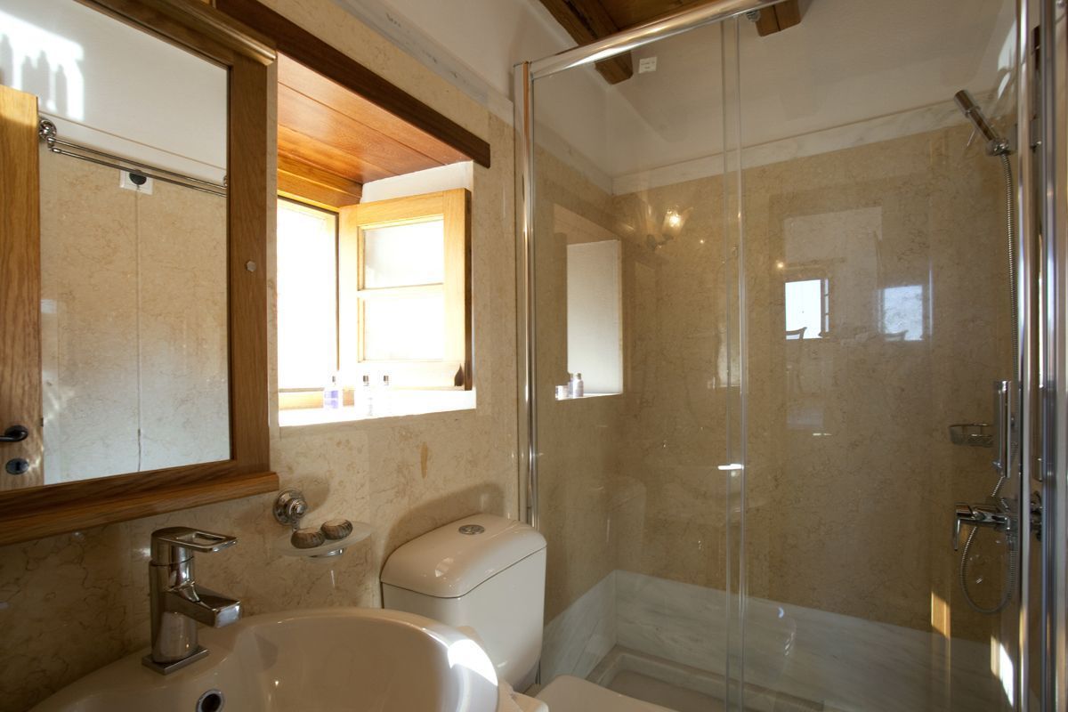 Un baño con ducha de vidrio, lavamanos e inodoro.