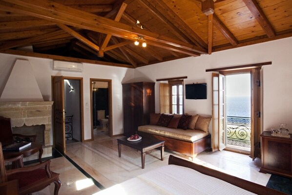Un salón amplio con techo de madera, un conjunto de sofás, una mesa de centro y vista al mar a través de un ventanal.