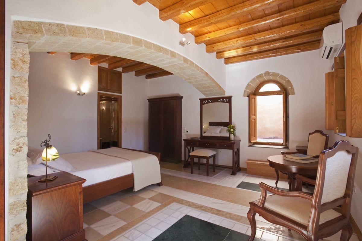 Un dormitorio con cama, escritorio, silla, espejo y ventana.