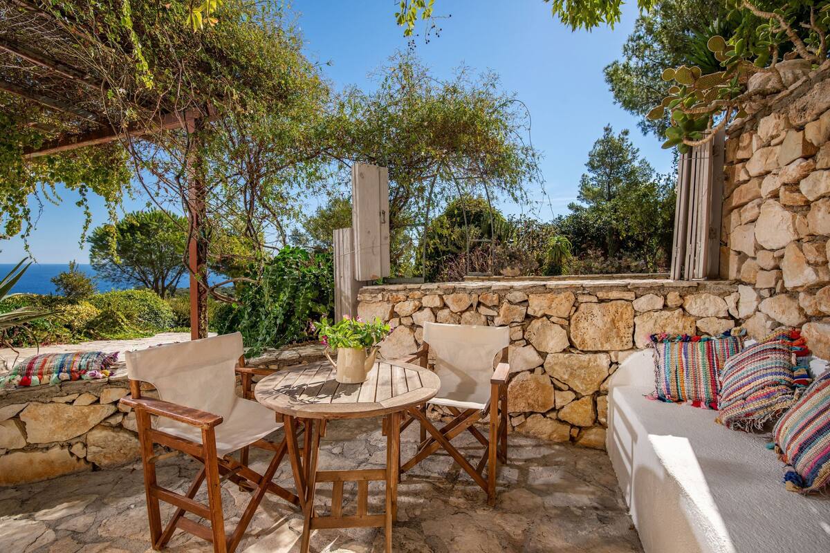 An outdoor seating area with stone walls, a round table, and chairs.