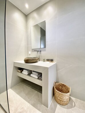 A modern bathroom with a large mirror, a bowl sink, and a woven basket. - Lithies Hotel (Zakynthos)