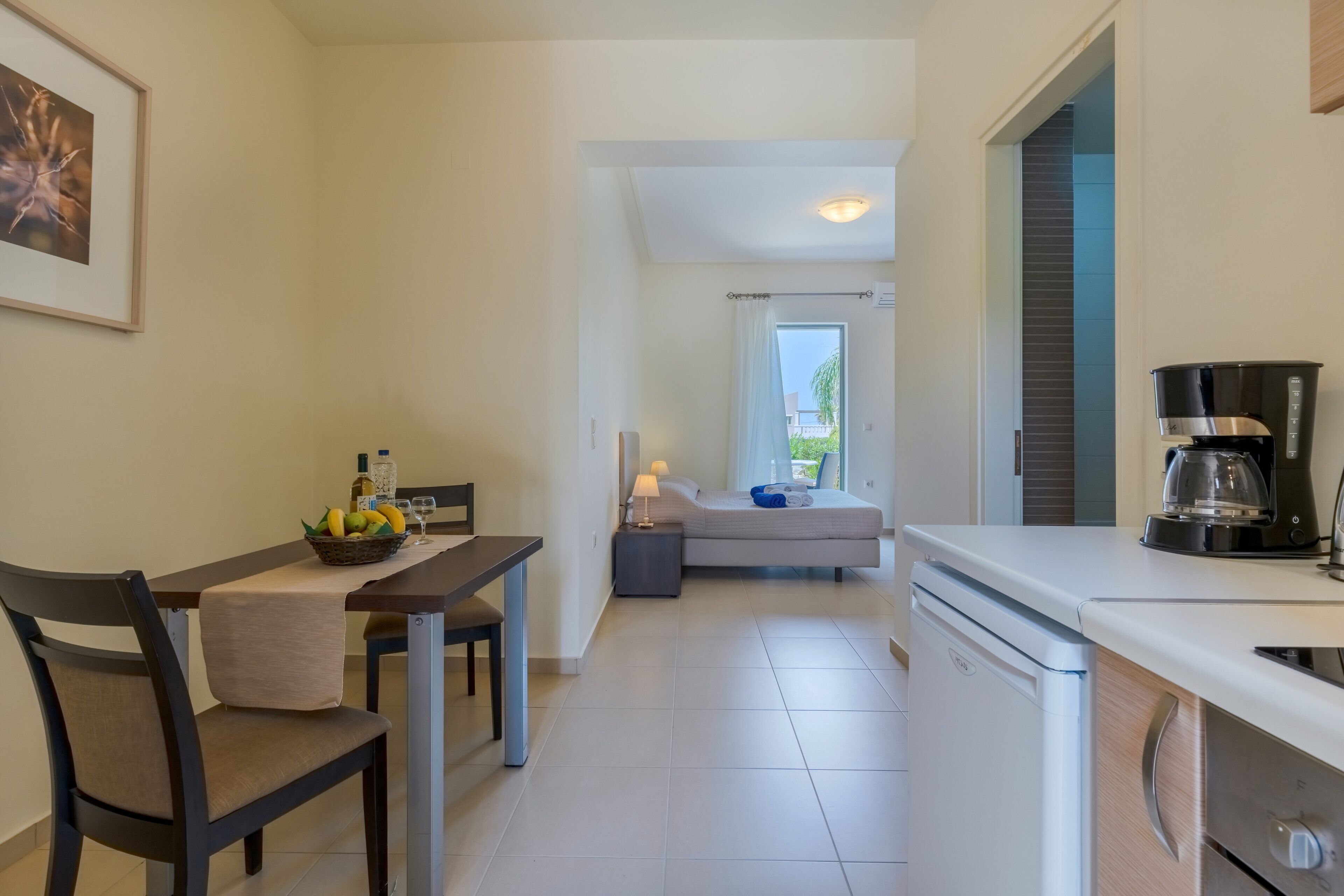 A modern kitchen with a dining area, a bed with a view, and a coffee maker.