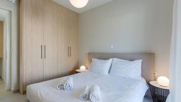 A modern hotel room with a large bed, two bedside tables with lamps, a wardrobe, and a neutral color scheme.