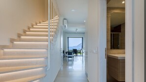 Un interior moderno con una escalera que conduce a un comedor, una cocina y vistas al mar.