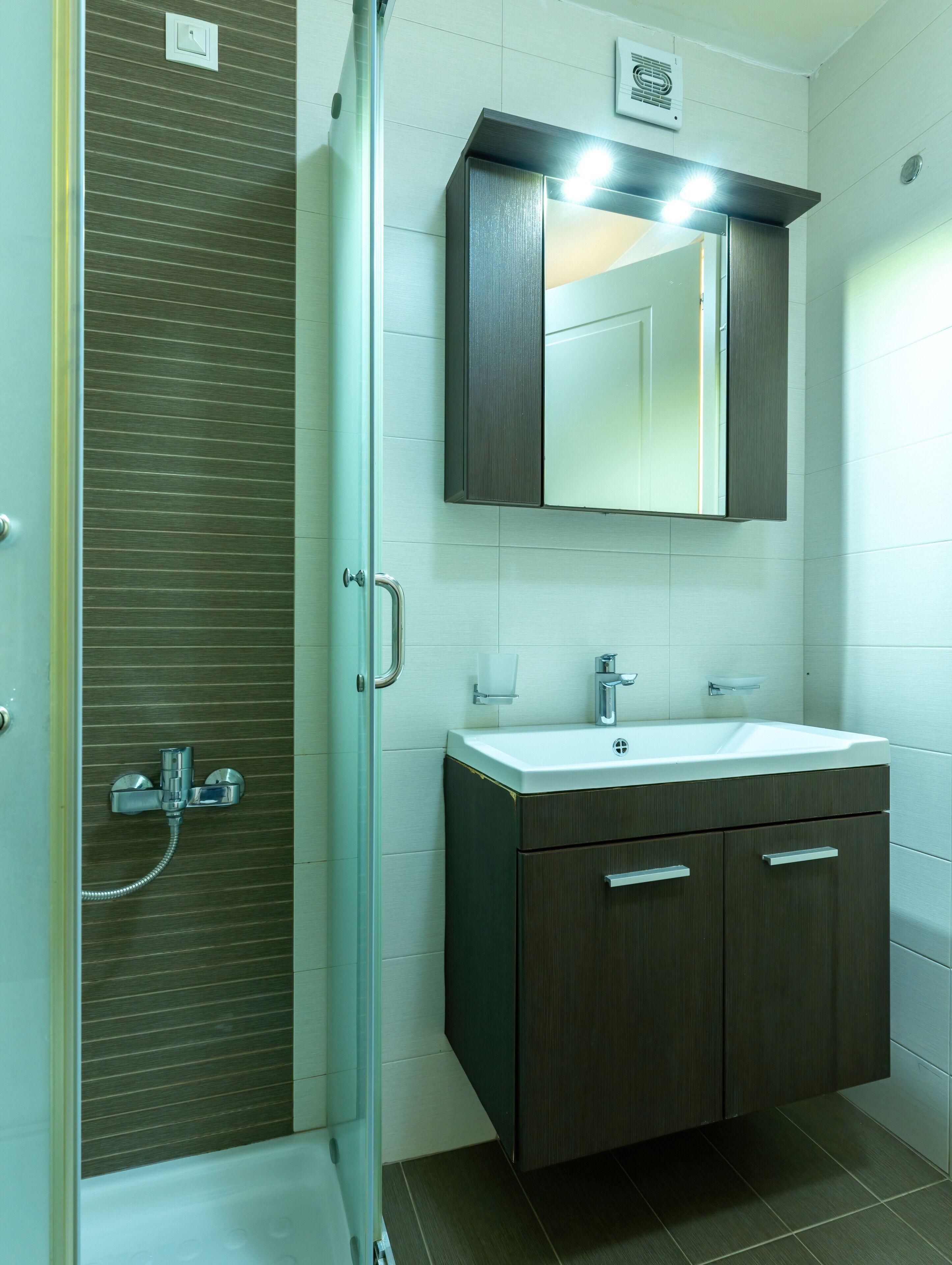 A modern bathroom with a glass shower enclosure, a vanity with a mirror, and a toilet.