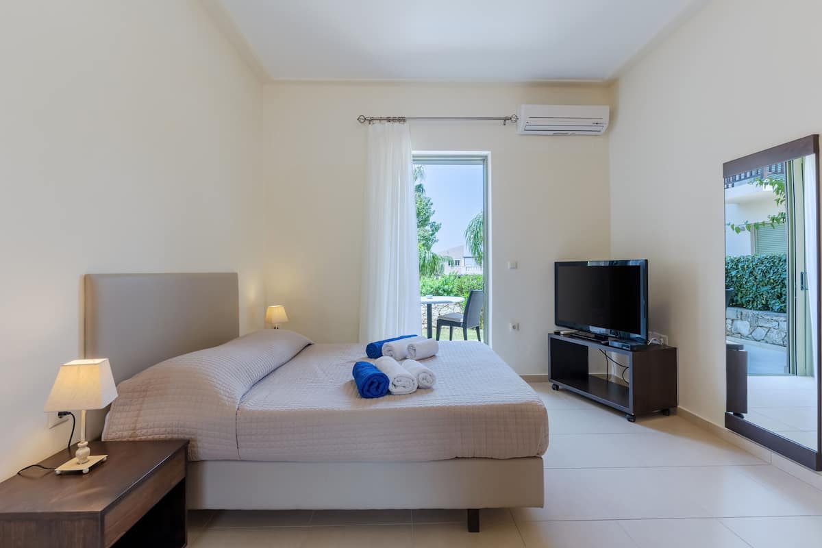 Una habitación de hotel moderna con una cama grande, televisión y vistas al exterior.