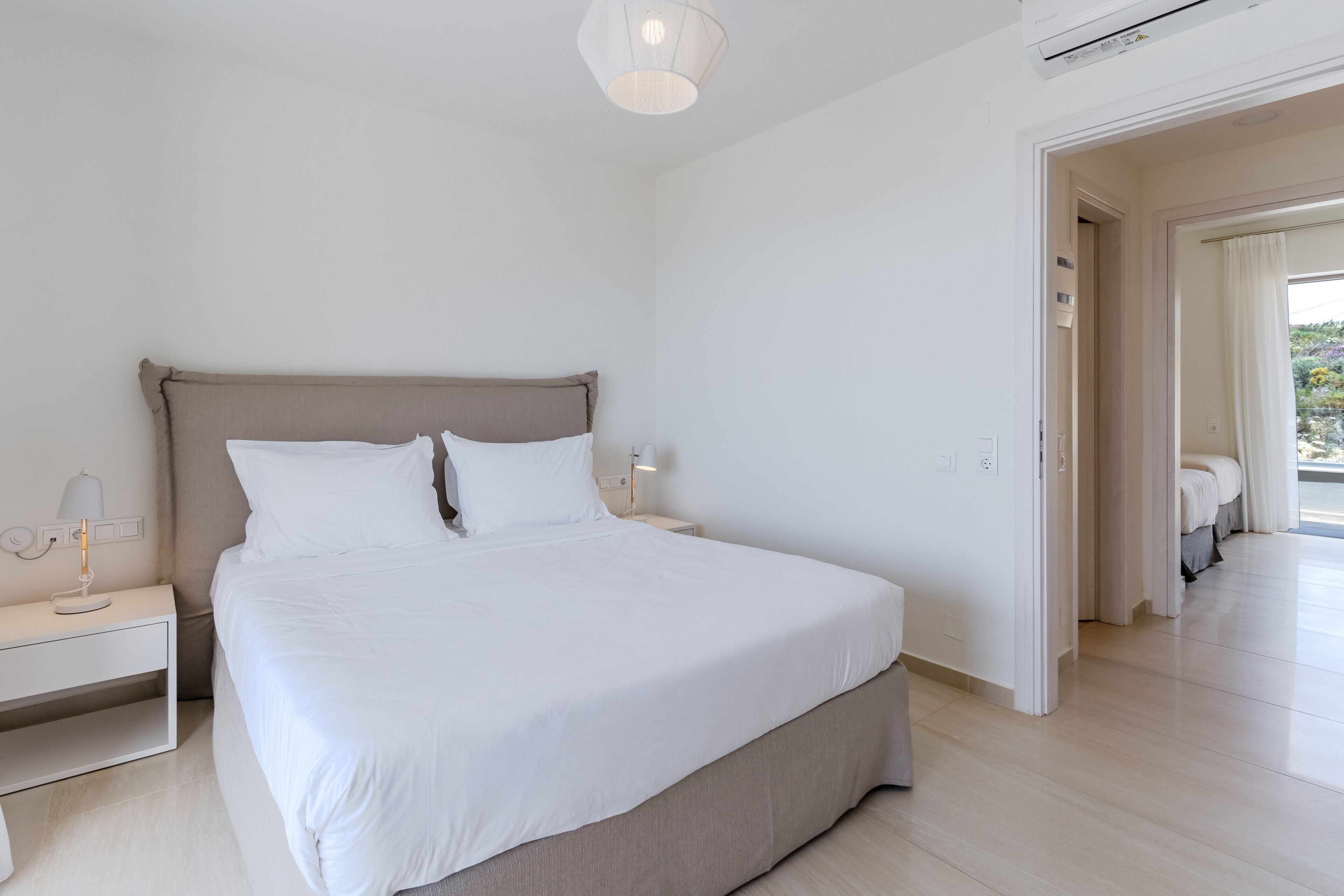 Un dormitorio moderno con una cama grande, mesitas de noche y una lámpara en el techo.