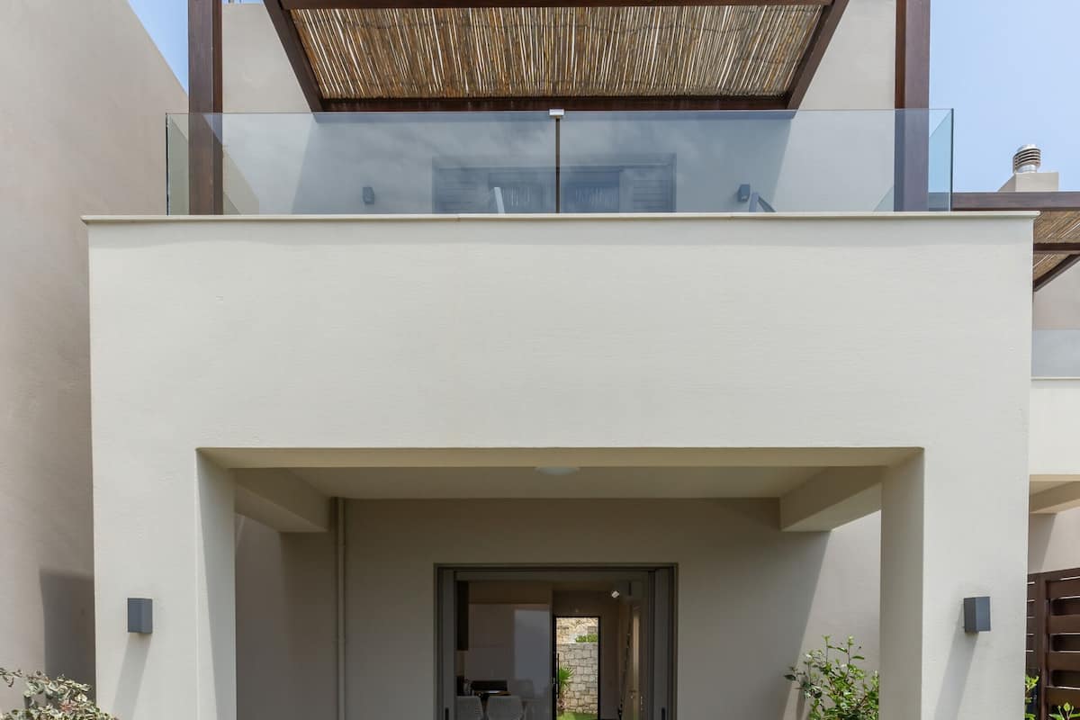 Una casa moderna de dos pisos con un porche cubierto, un comedor y una silla de descanso.