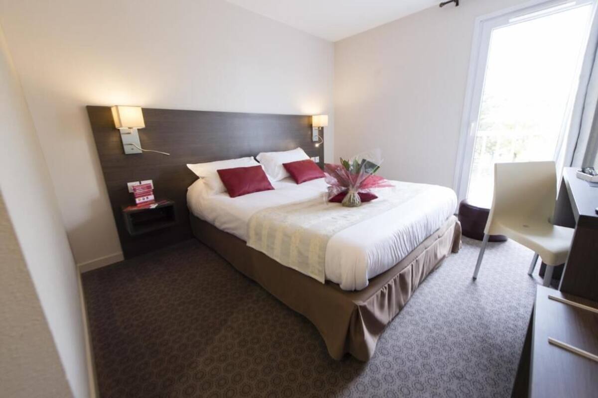 A hotel room with a large bed, two bedside tables, a desk, and a chair.
