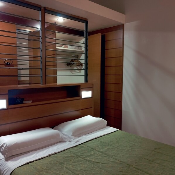 A bedroom with a bunk bed, a wardrobe with a mirror, and a bedside table with a lamp.