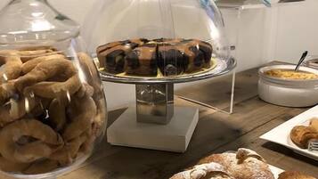 Ein reich gedeckter Büfett mit verschiedenen Gebäcken und Desserts, darunter eine Kuchenplatte und eine Obstschale.