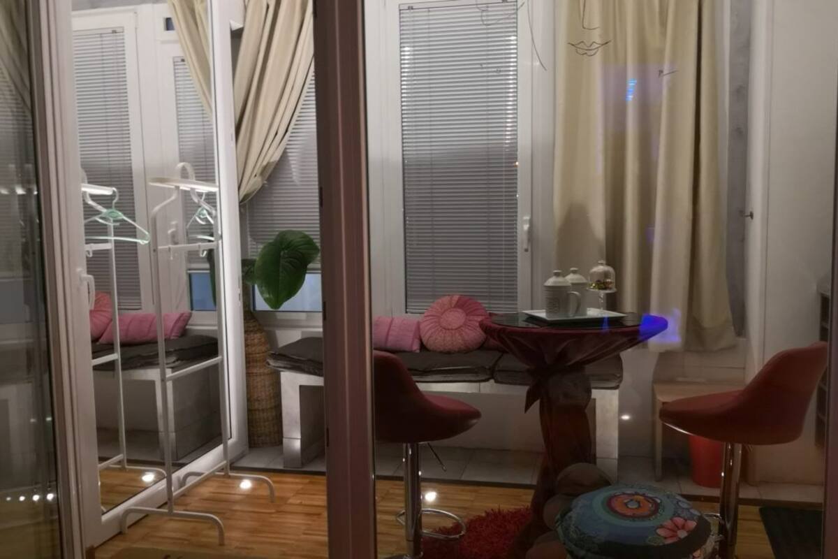 A compact living space with a kitchenette, a dining area with a table and chairs, and a window with blinds.