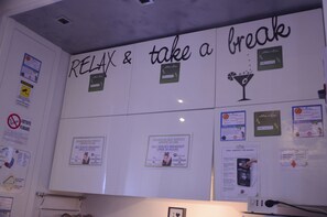 Una pared con varios avisos y carteles, incluyendo un llamativo letrero que dice 'RELAX & take a break'.
