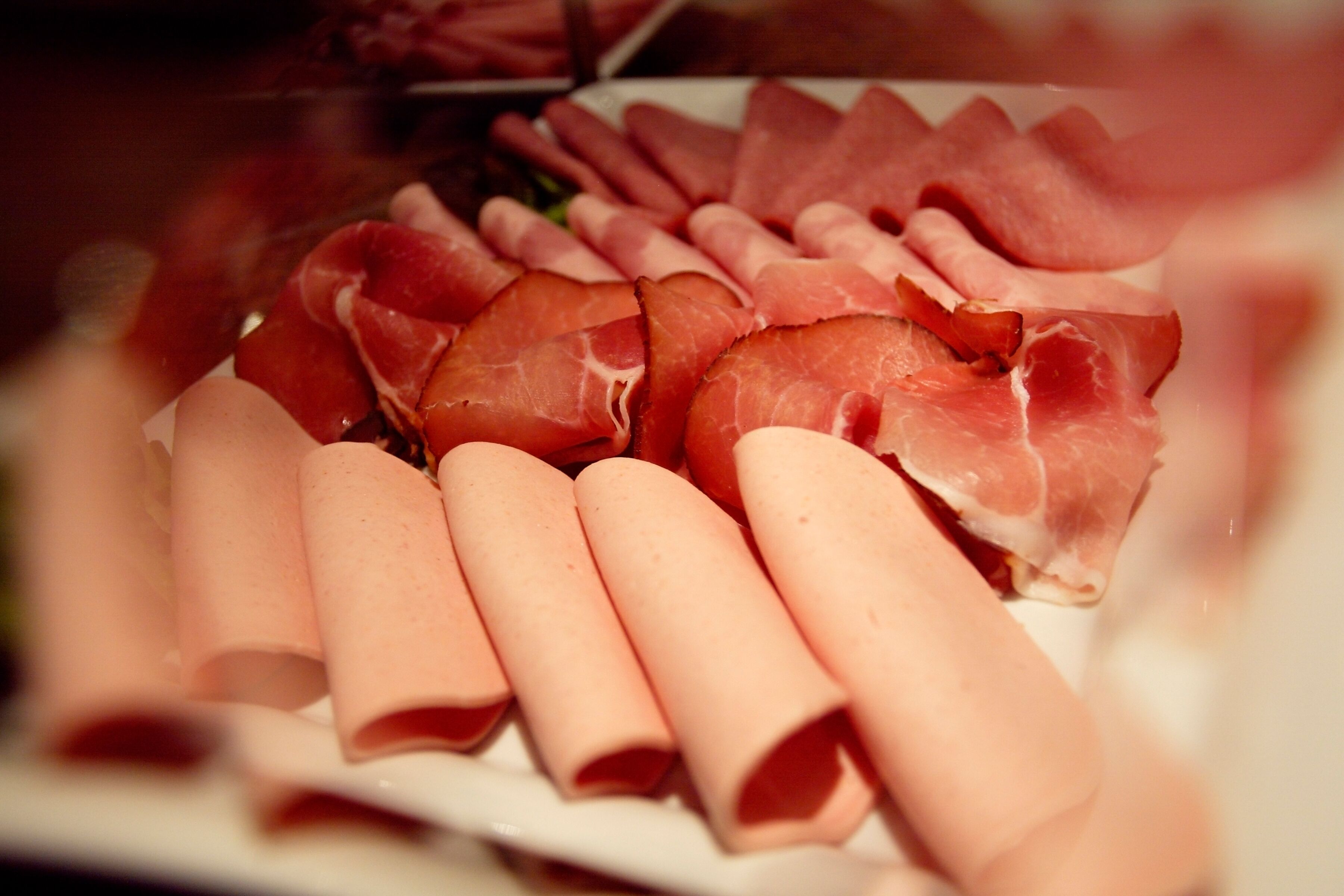 Eine Platte mit verschiedenen Sorten luftgetrockneten Fleischwaren, darunter Prosciutto und Salami, auf einem weißen Teller.