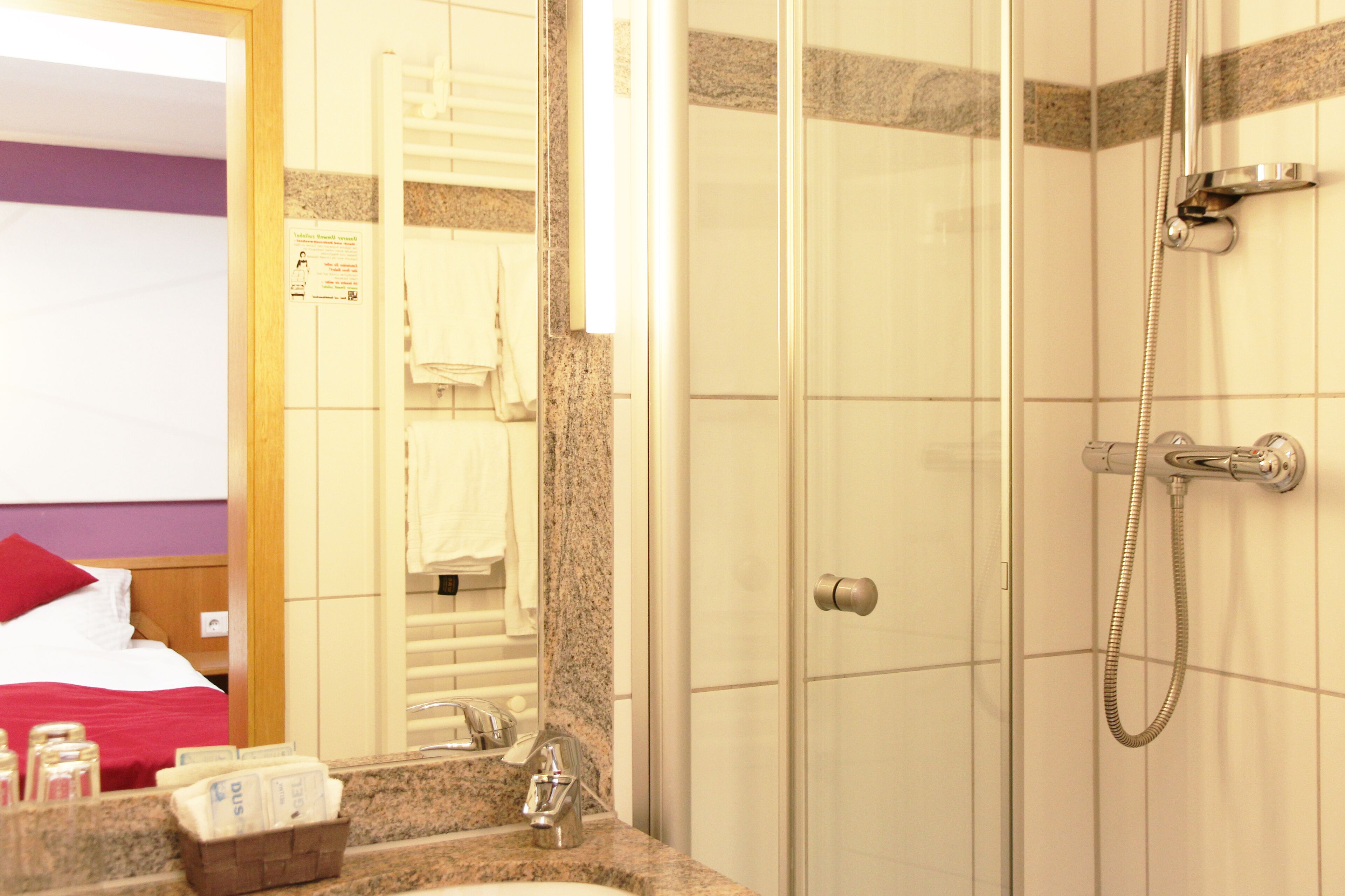 Un baño de hotel con ducha, lavabo y espejo.