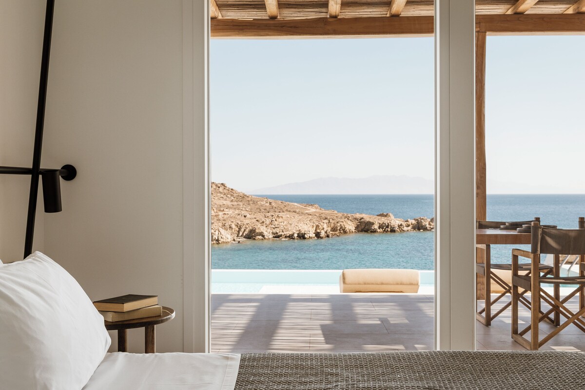 Une chambre avec vue sur la mer, une table en bois et une chaise.