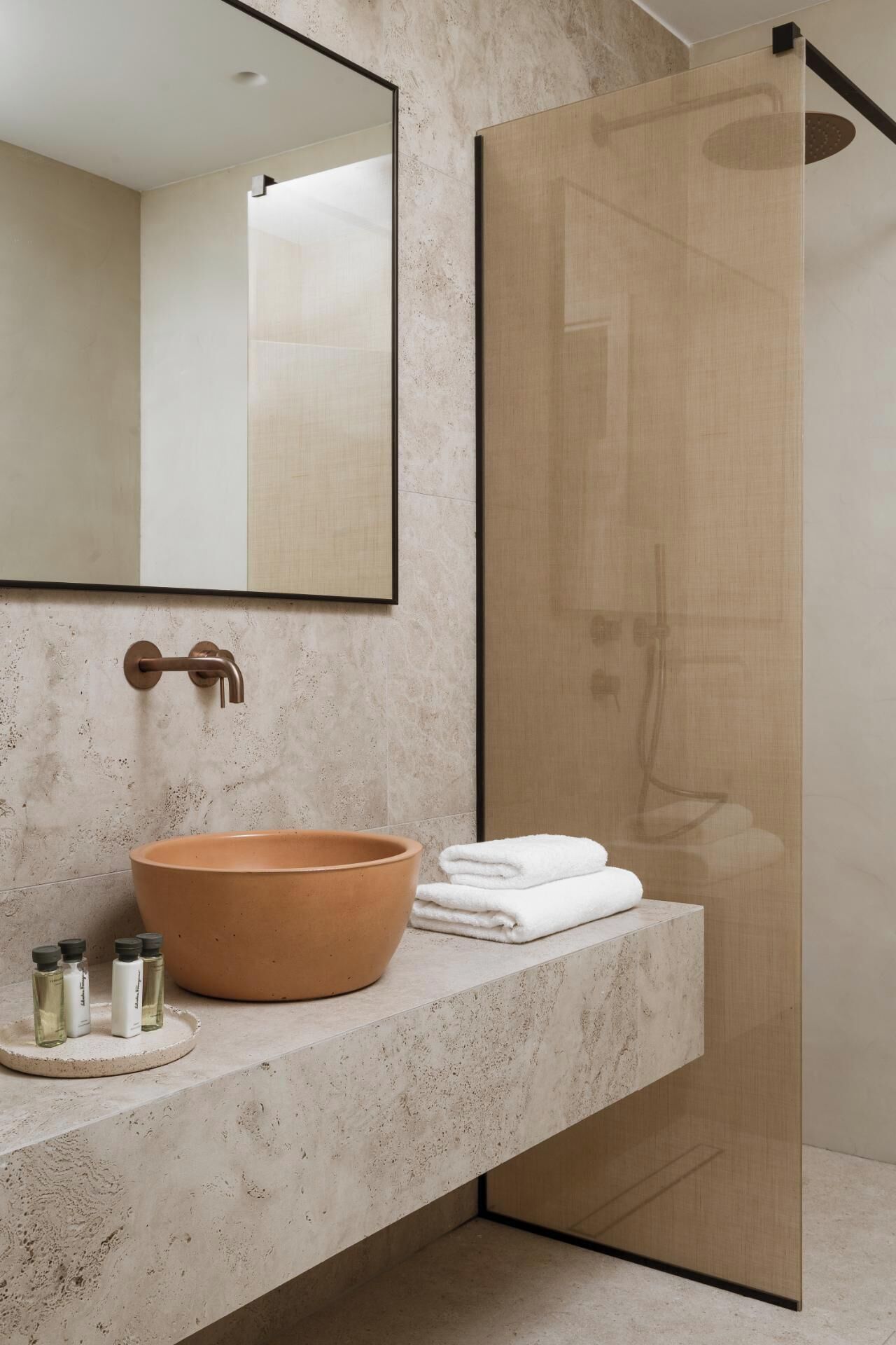 A modern bathroom with a large mirror, a round ceramic sink, and a glass shower enclosure.