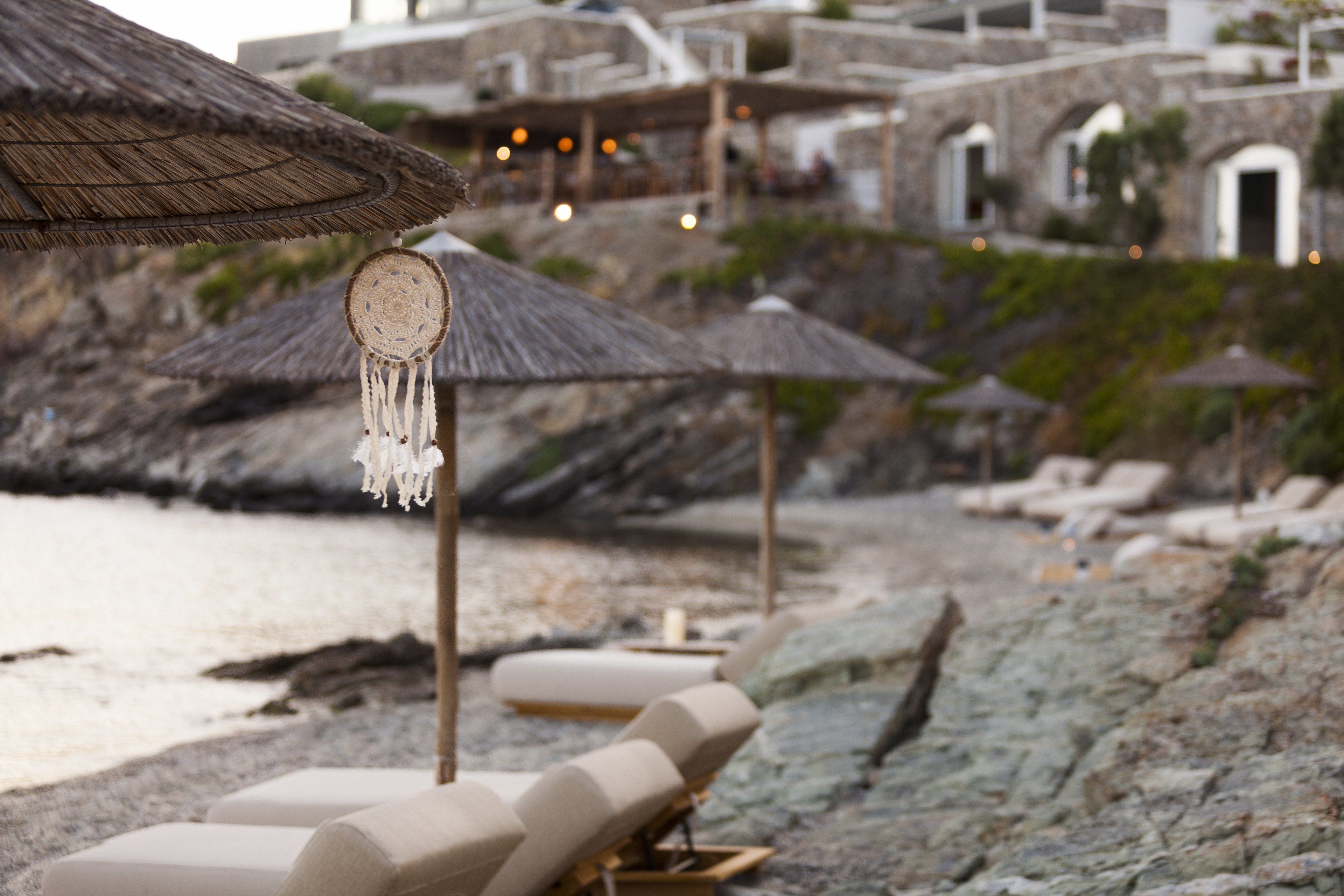 Una playa con sillones de descanso y sombrillas de paja.
