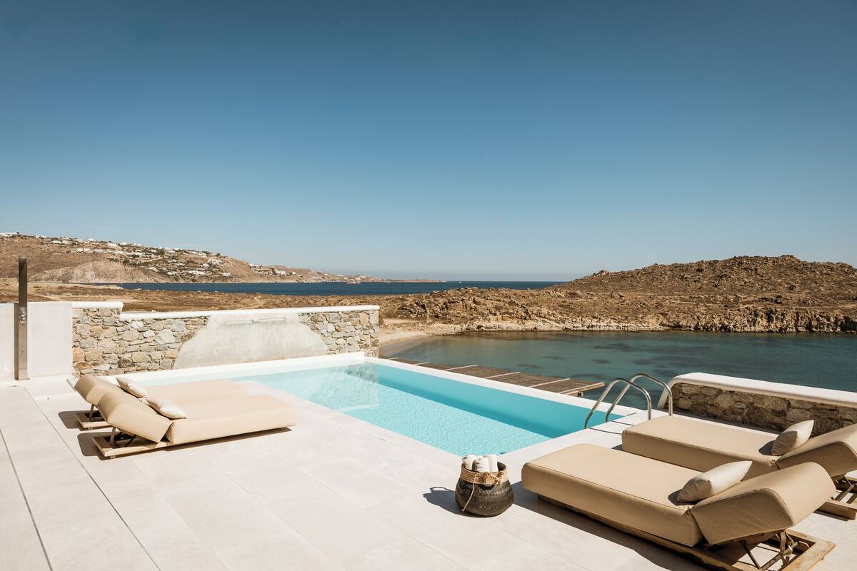 Un espace aménagé au bord de la piscine, avec des chaises longues et une vue sur la mer.